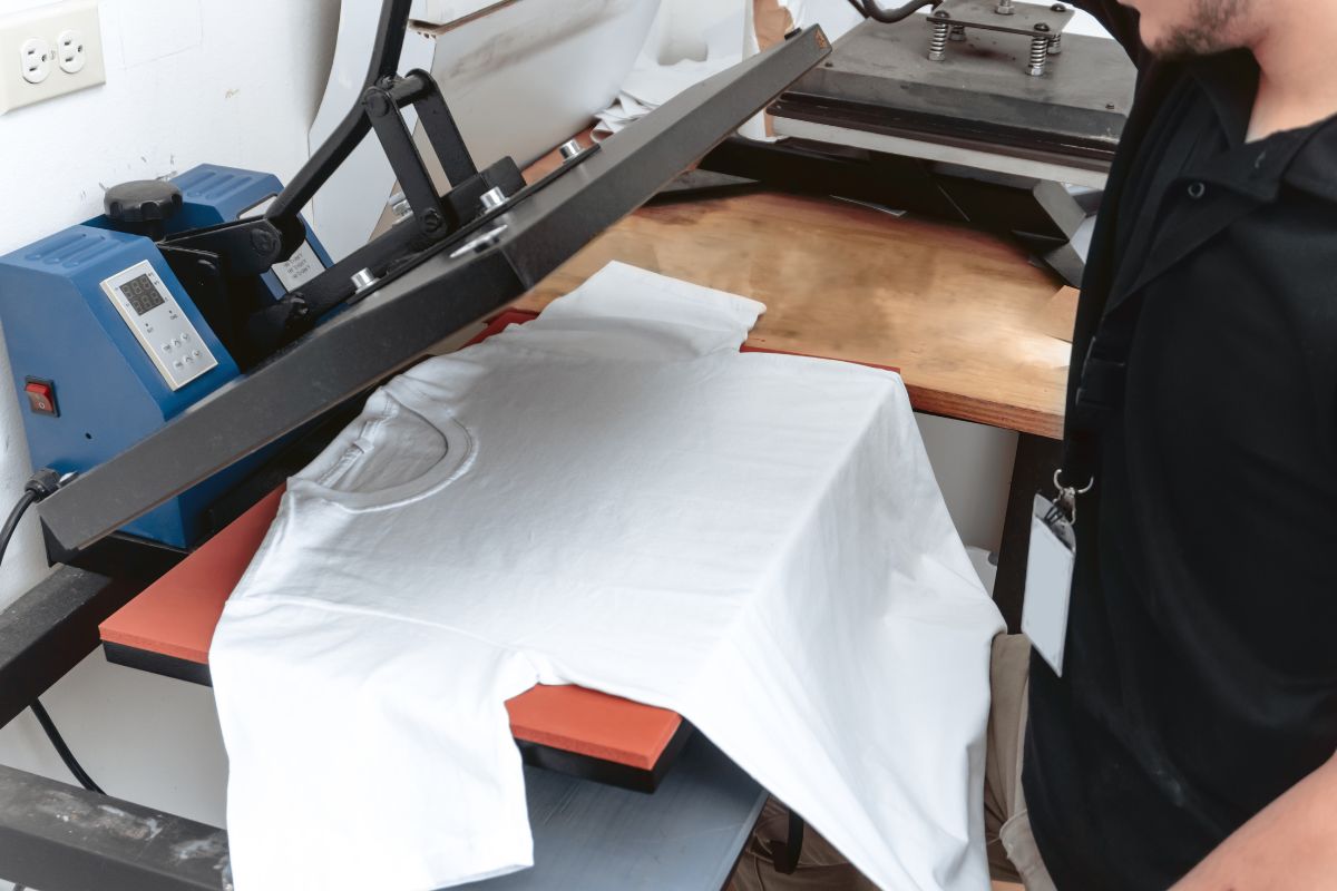 A guy printing art on the shirt by the sublimation printer.