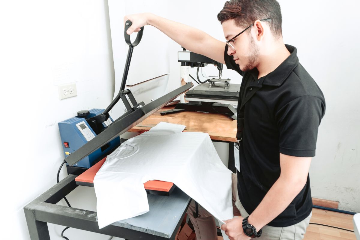 A person Designing T Shirt with help of printing machine.