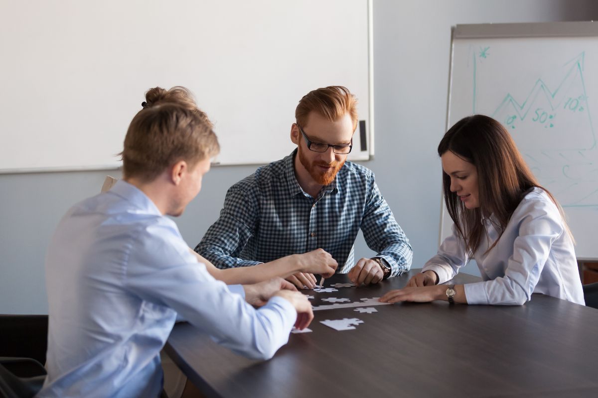 Employees solving puzzle with each other for better collaboration and understanding.