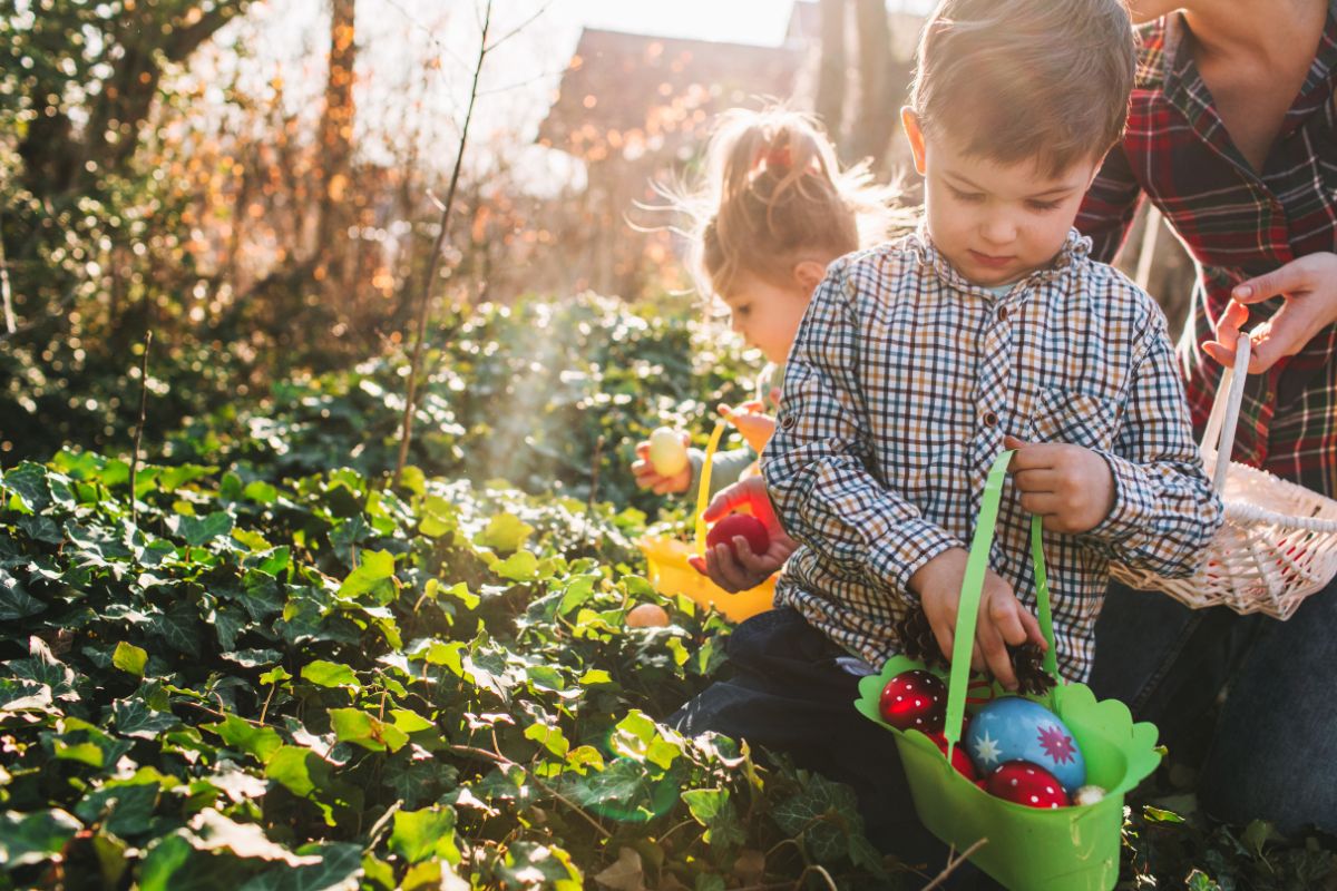 Kids carrying colourful easter eggs walking through garden