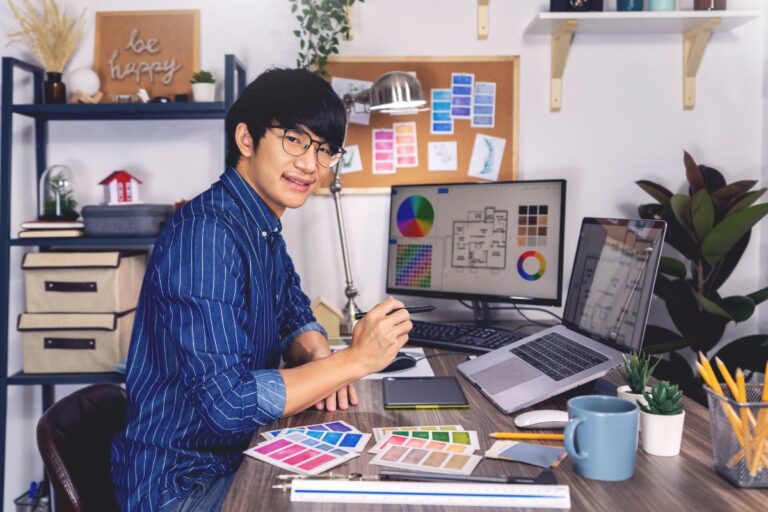 Man using vector file to make design on laptop and desktop