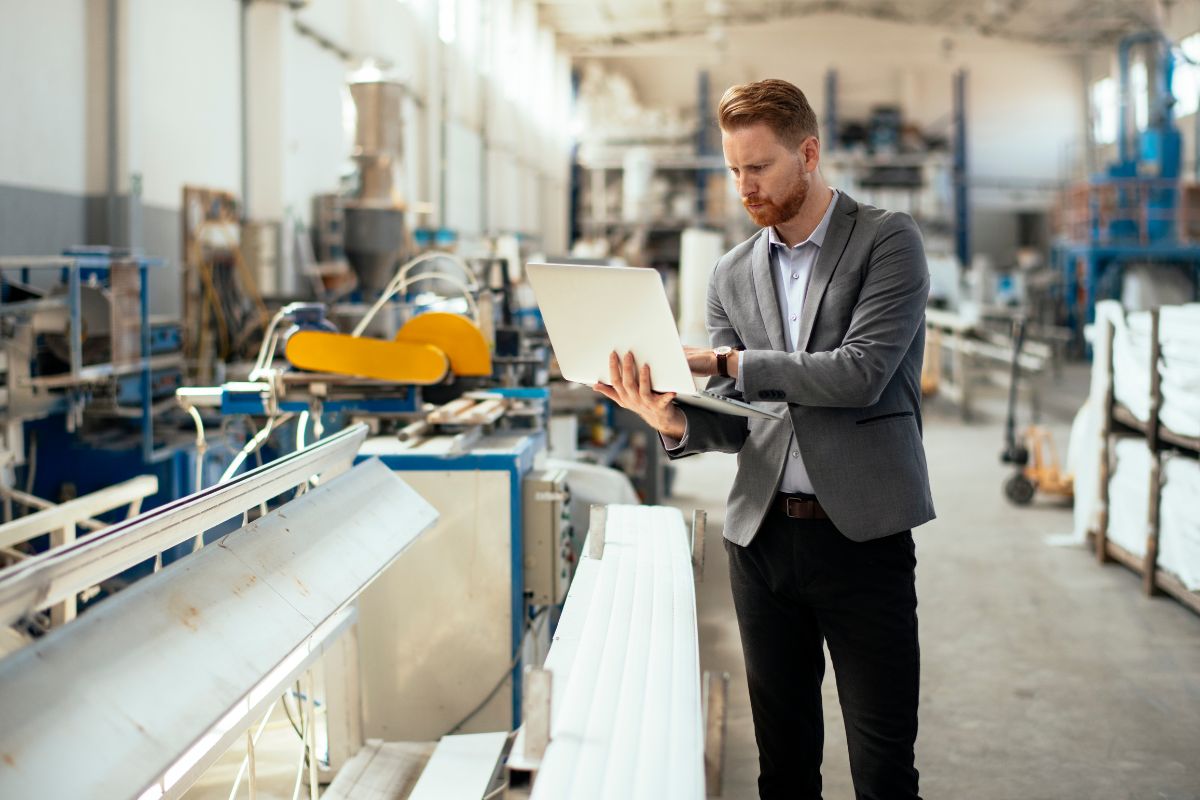 Man working on laptop handling business operations in a factory