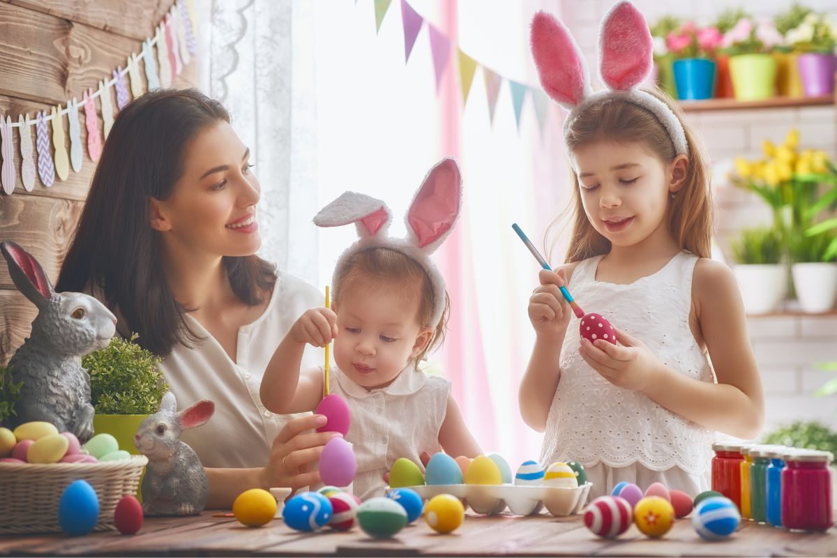 Mother is helping to decorate eggs with kids to celebrate easter colours