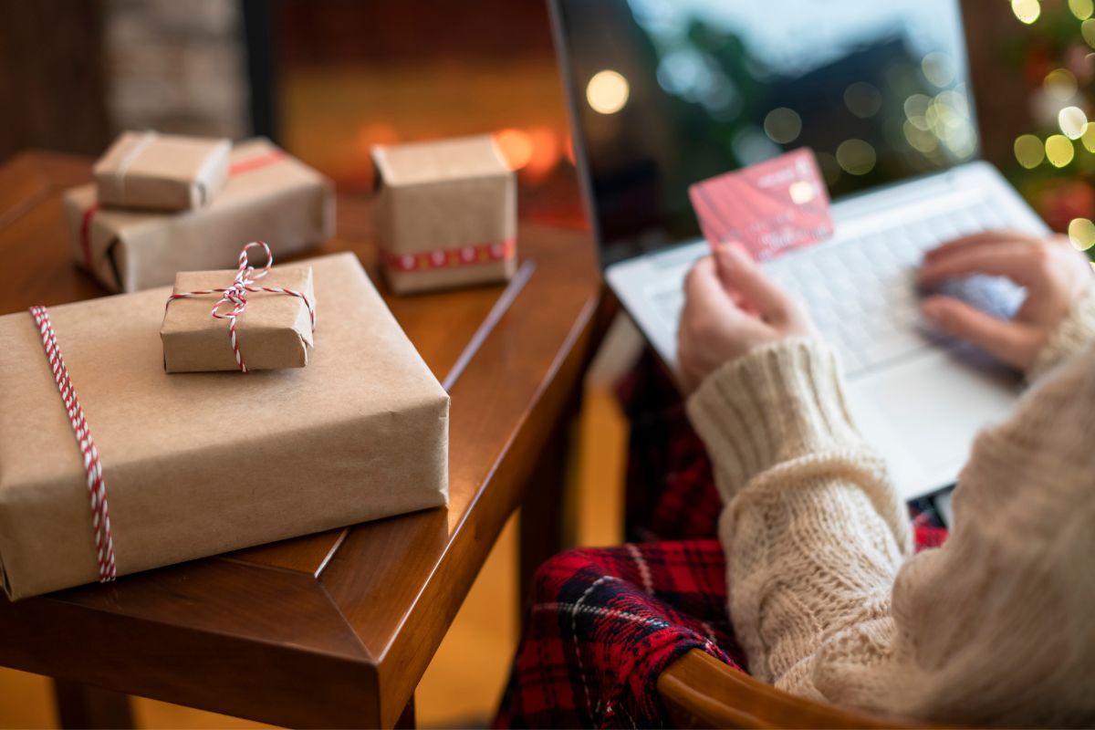 Woman holding credit card using laptop for making order online from employee swag store