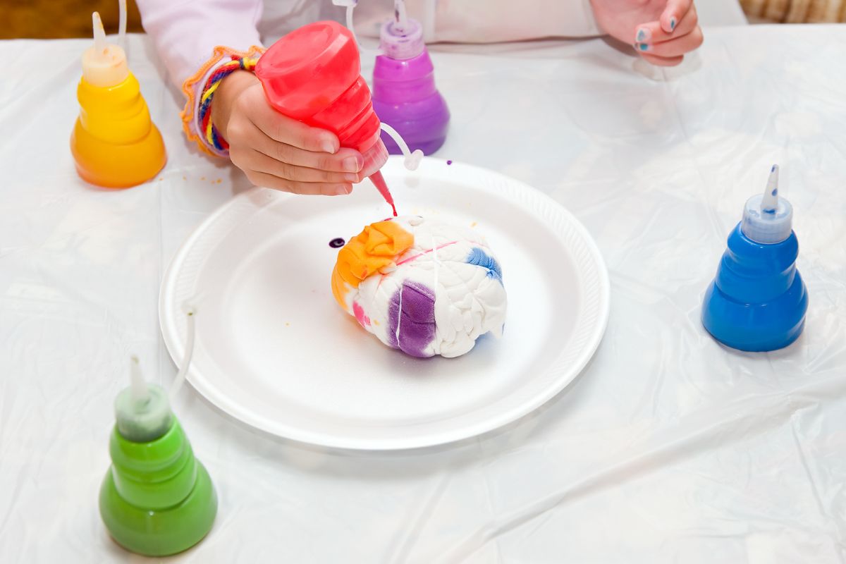 Woman is dyeing fabric in tie dye colors