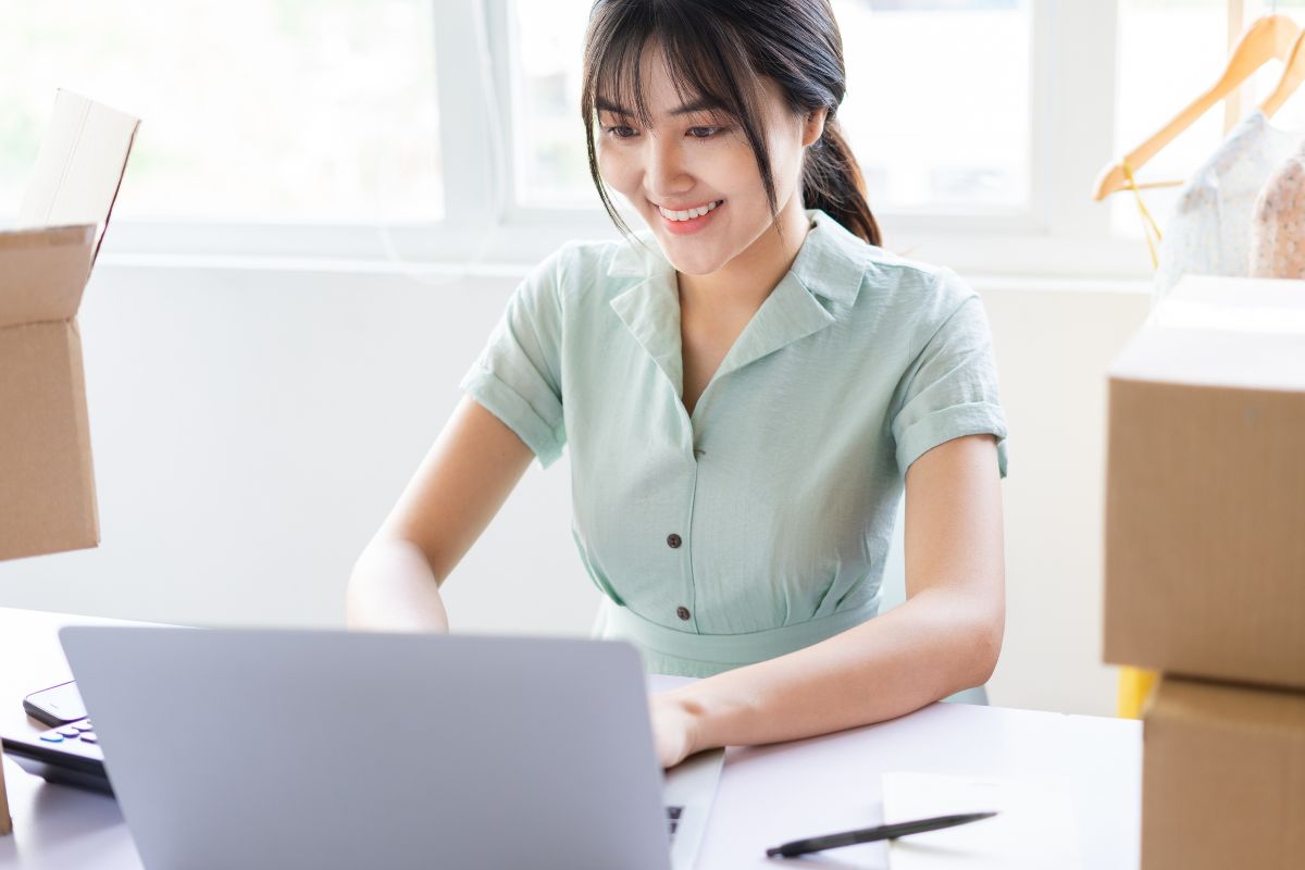 Woman running small business working on laptop to create custom swag