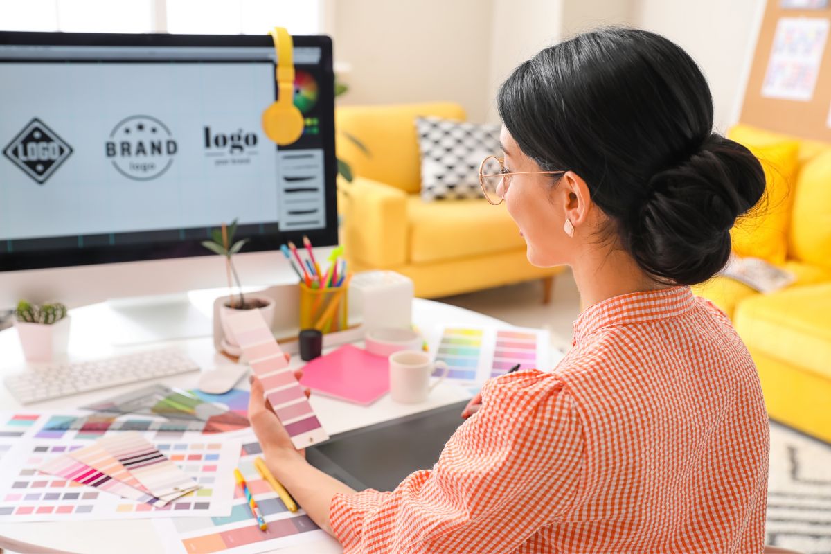 Woman selecting colors to design logo on her desktop using vector file