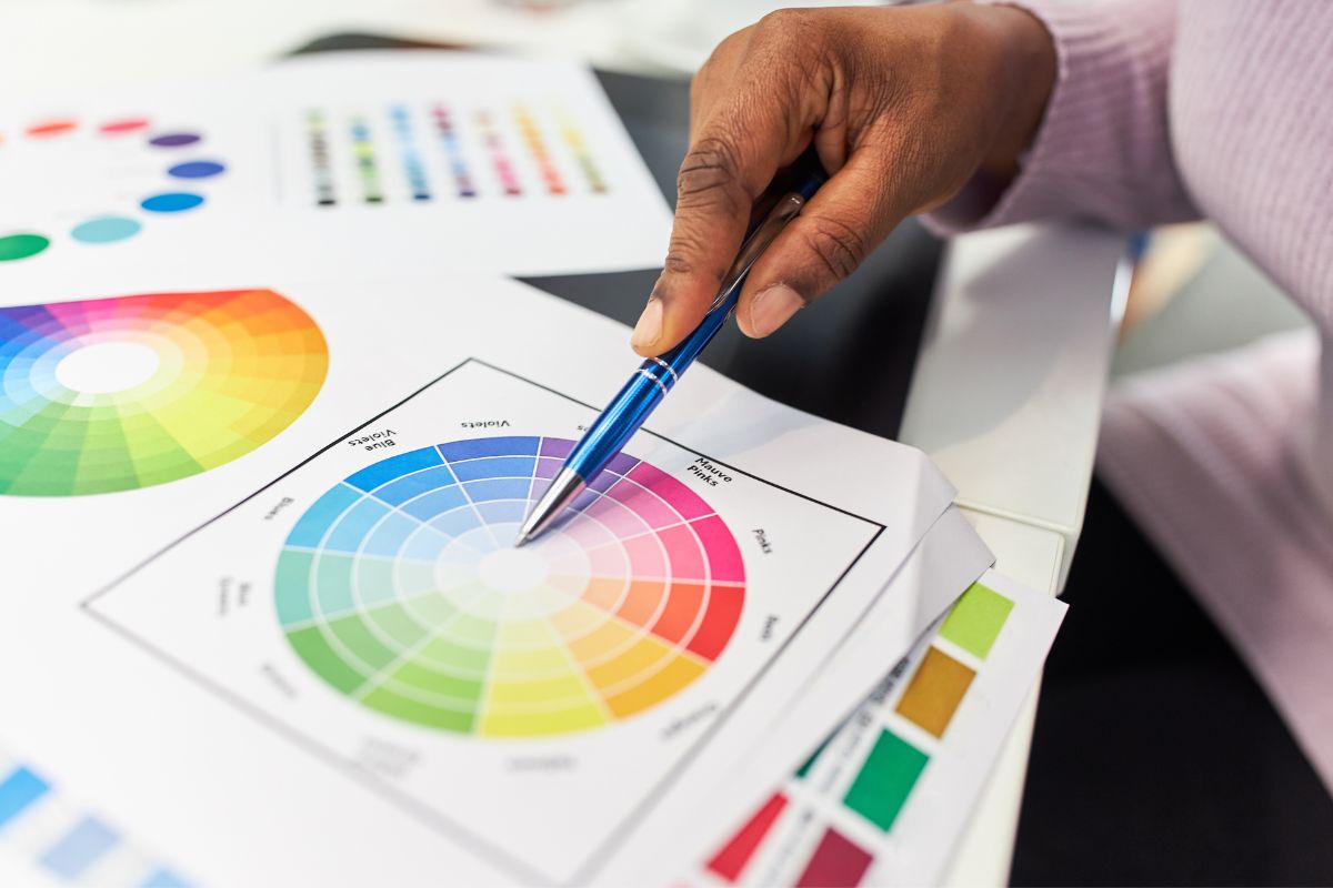 Person pointing pen at color sample of hex code to cmyks on table