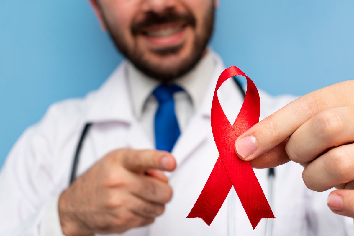 A doctor holds a red ribbon representing HIVAIDS awareness