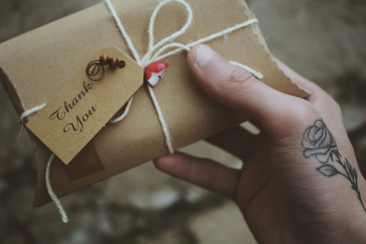 A hand holding a personalized gift for the client along with a handwritten thank you note