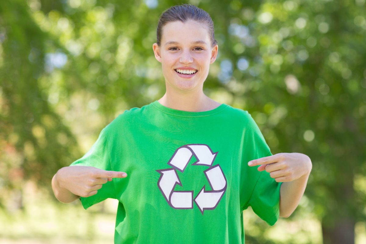 A similing woman pointing to her trendy green t shirt