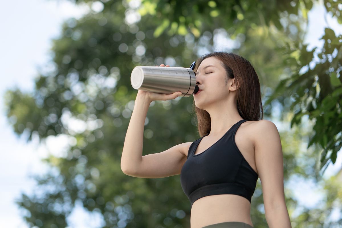 A woman hydrating with a tumbler after a workout