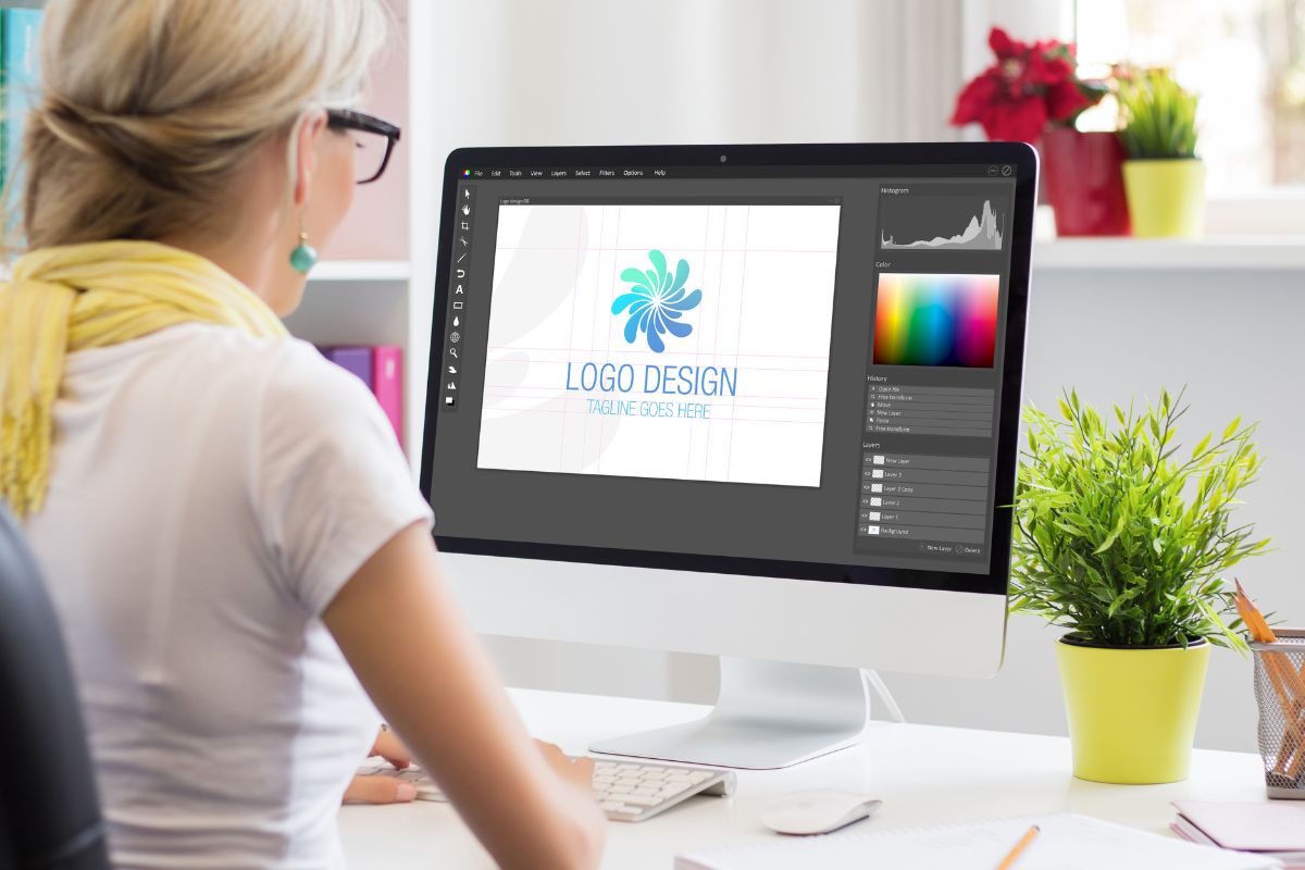 A woman is designing a logo for a t shirt on her laptop using a vector file