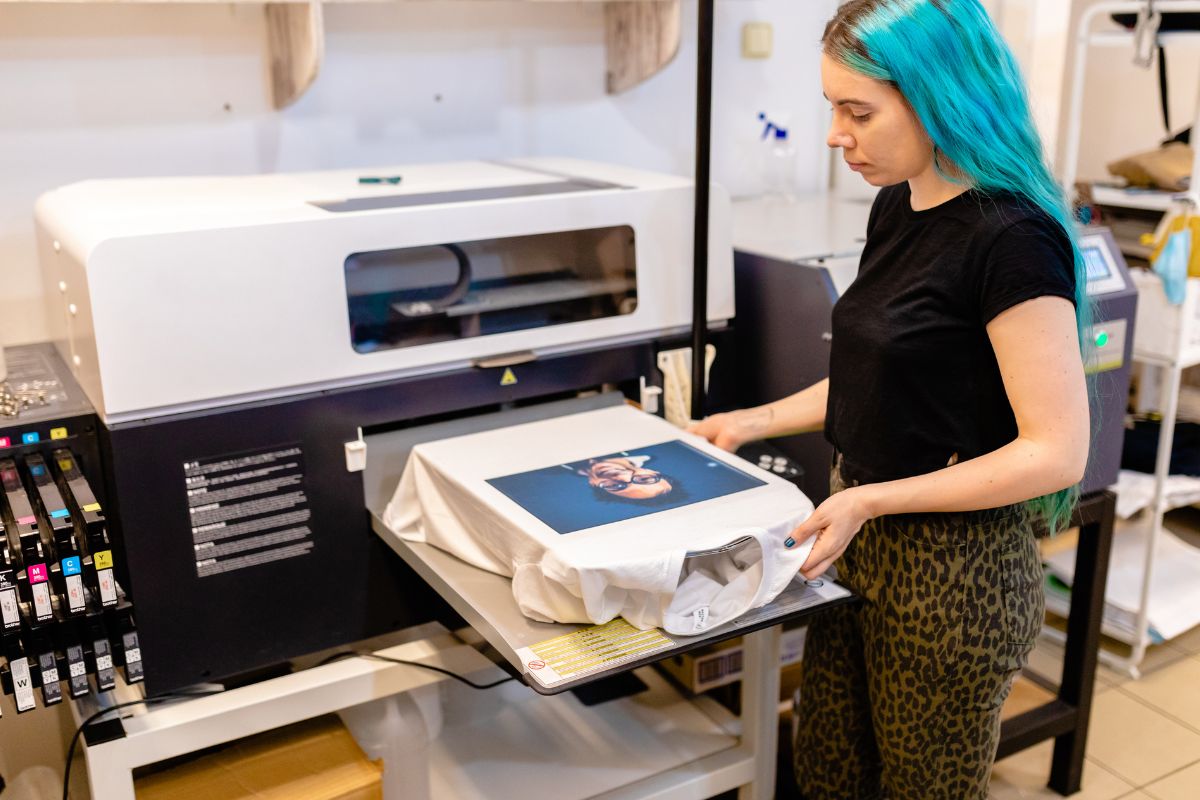 A woman prints a T shirt using printing machine
