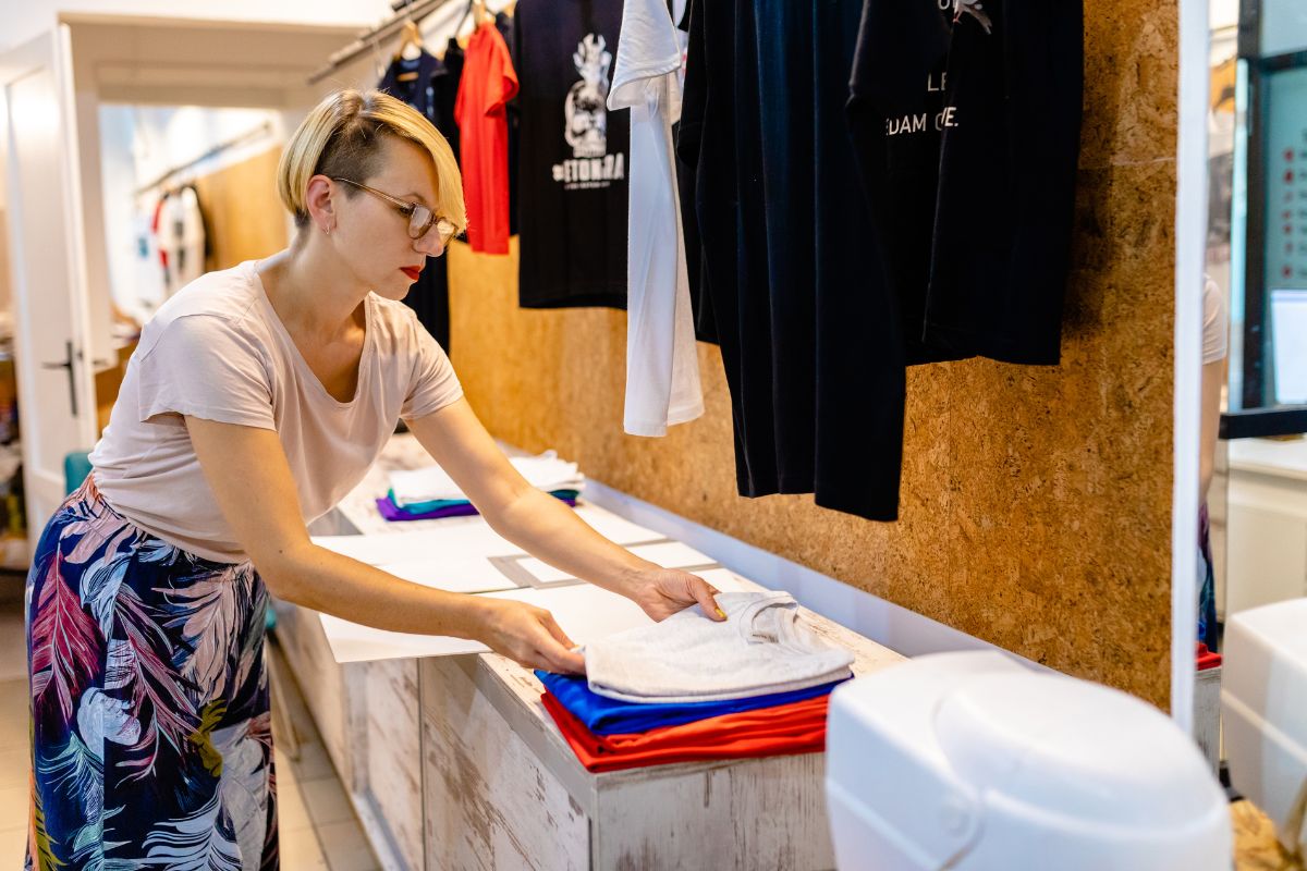 A woman stacks designed t shirts in a cloth store