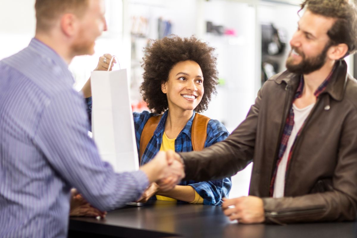 Customer shakes hands with the shop attendant in gratitude for receiving their print on demand product