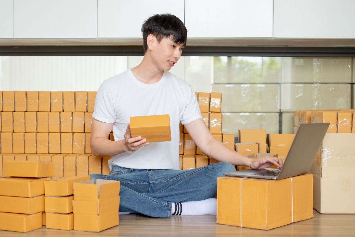 Guy using laptop surrounded by print on demand inventory