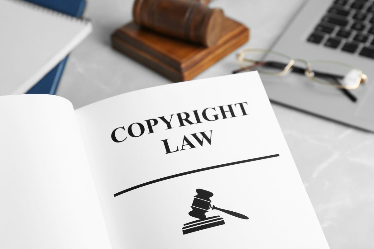 The word copyright is written on a book accompanied by a gavel and laptop on the table