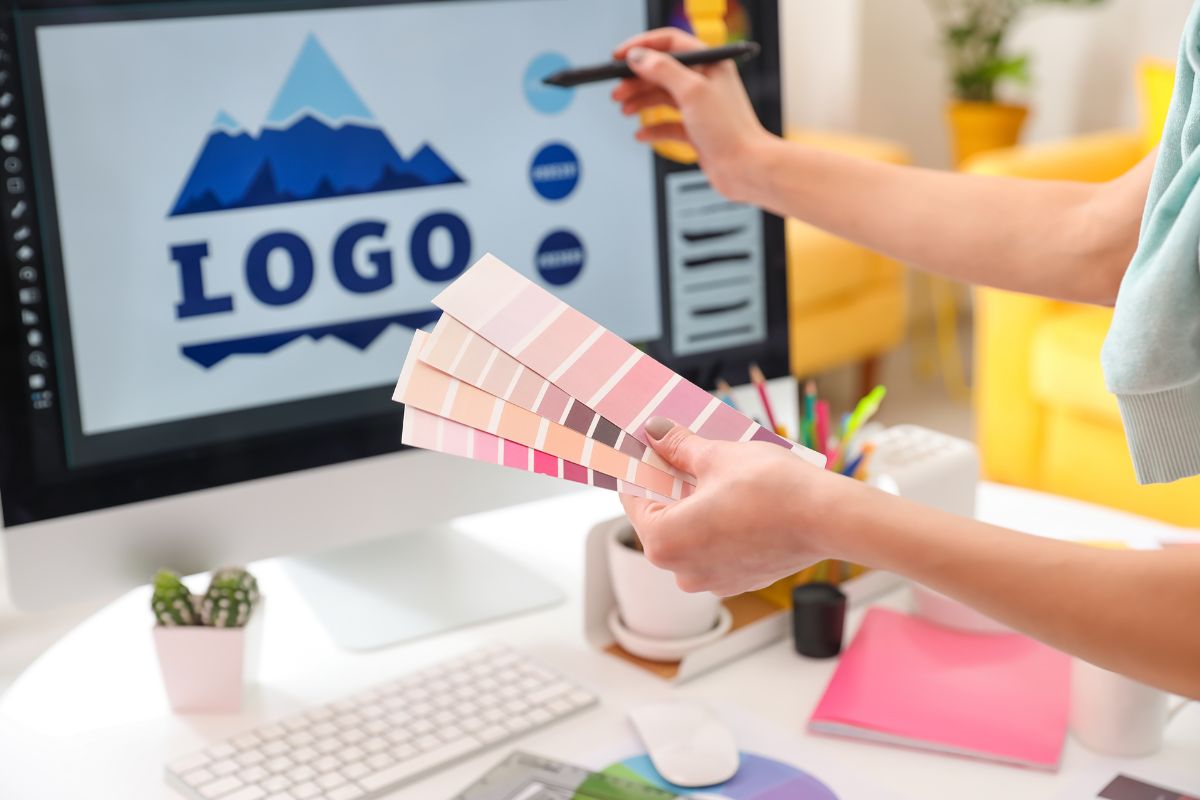 Woman designing logo size on computer for t shirt with palette paper in hand