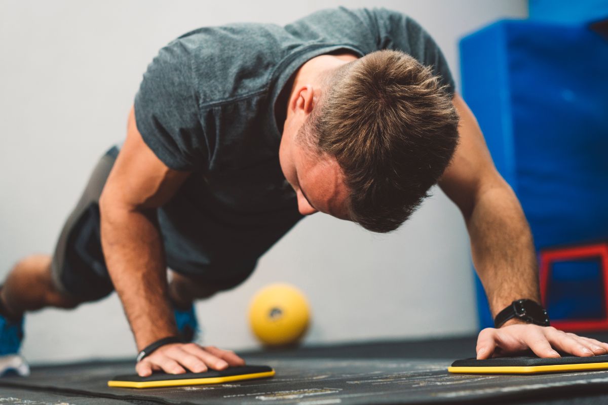 A guy excercising while wearing muscle fit t shirt at the gym.