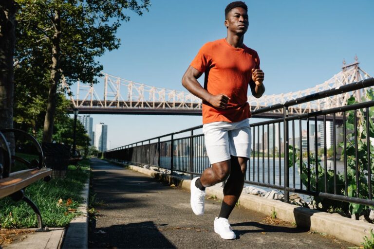 A guy is jogging in a snug fitting orange athletic t shirt