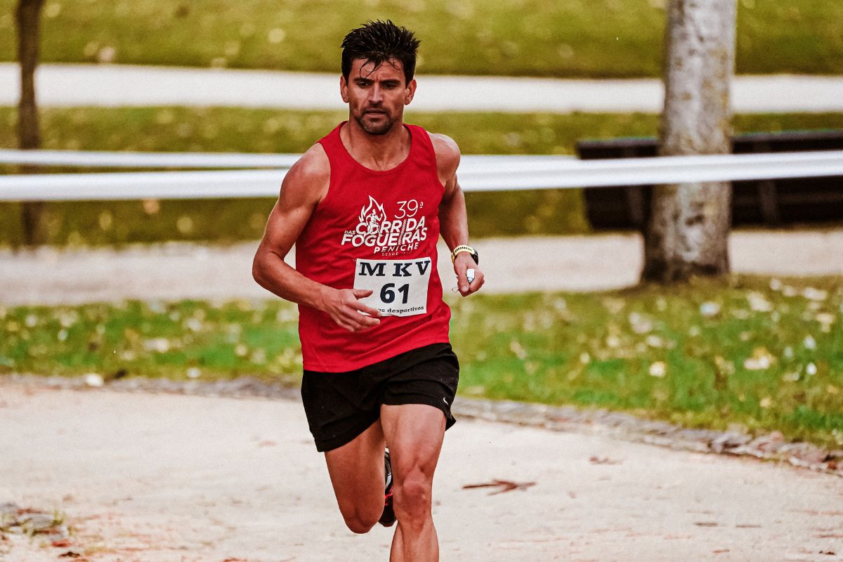A guy running while wearing racing tank top with details printed on it