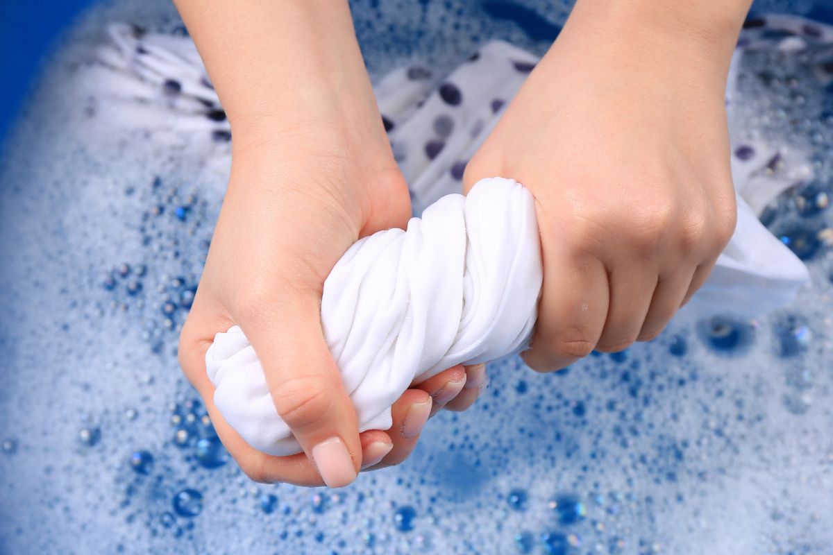 A lady soaking polyester cloth in water to prevent shrinking