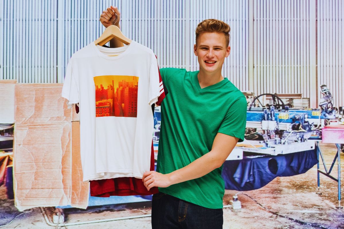 A man is showing a printed white t shirt