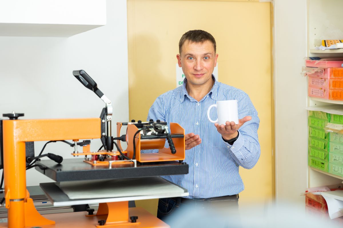A person printing on mugs in his workshop.