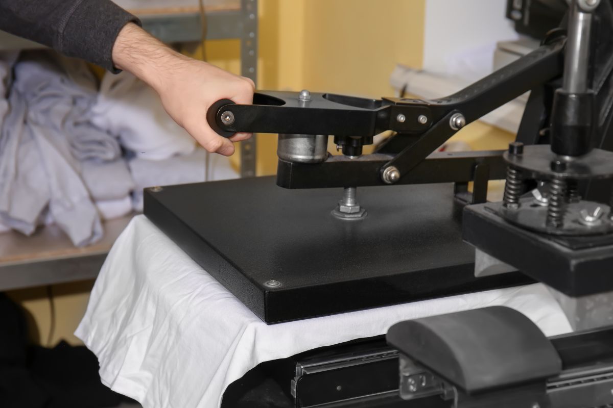 A person printing qr code on a white t shirt with the help of a machine