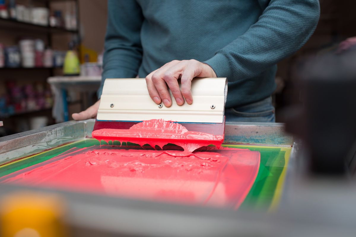 A person using screen printing technique on t shirt.