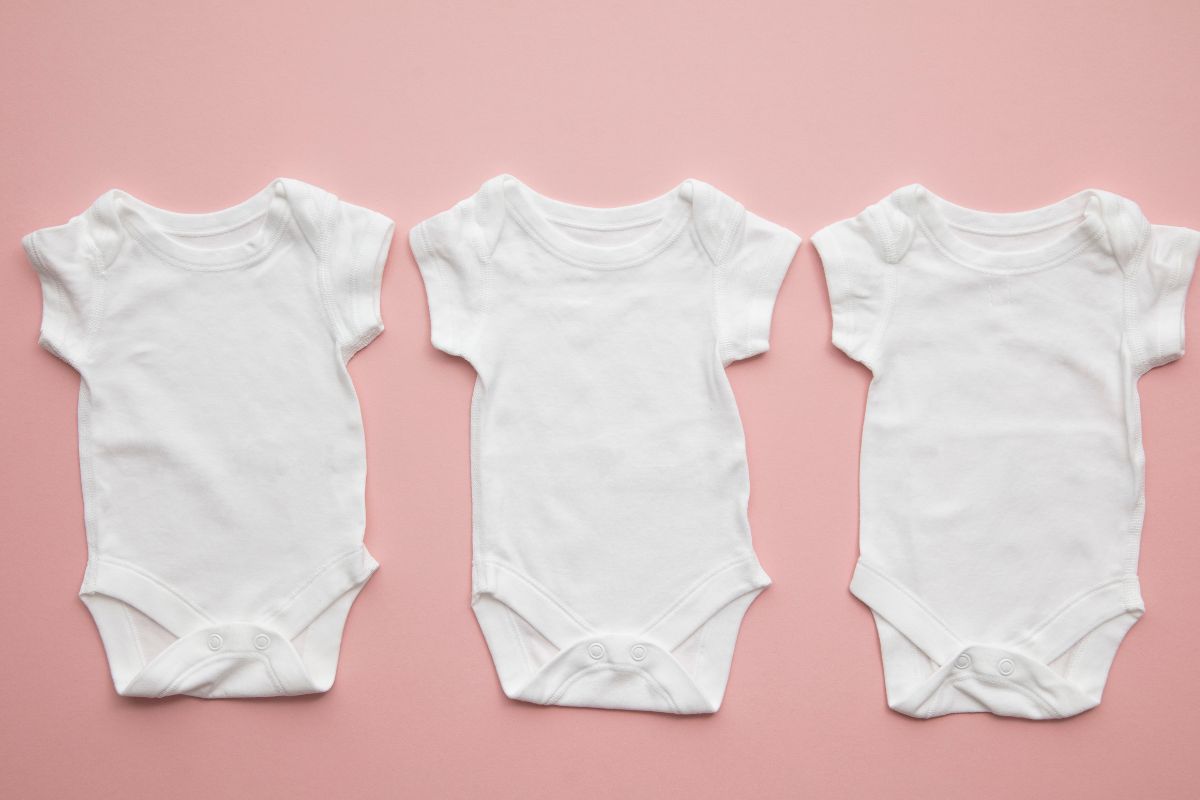 A set of three gender neutral white baby body suite