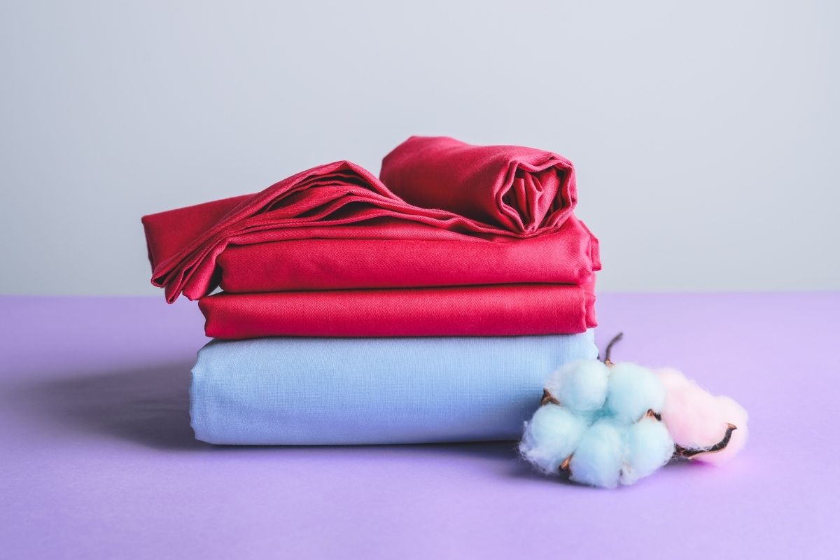 A small pile of cotton bedsheet kept with cotton plant