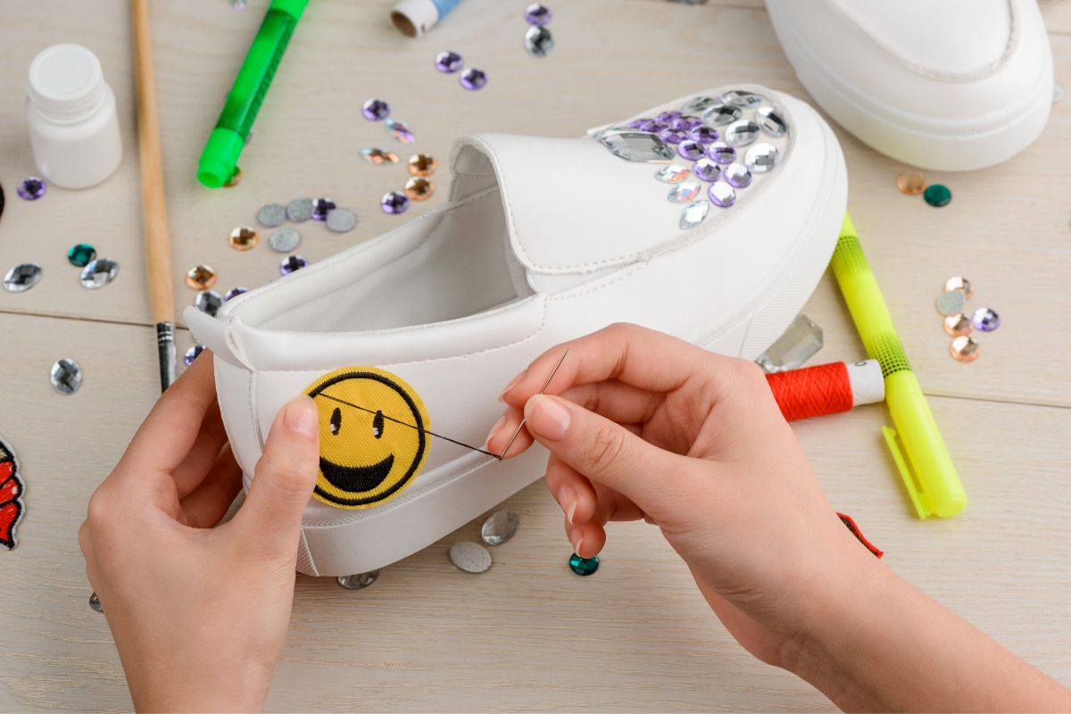 A woman is sewing a patch onto her shoes