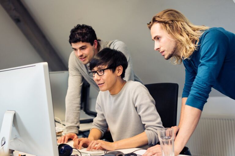 Men in T shirts are working on laptops in a corporate office