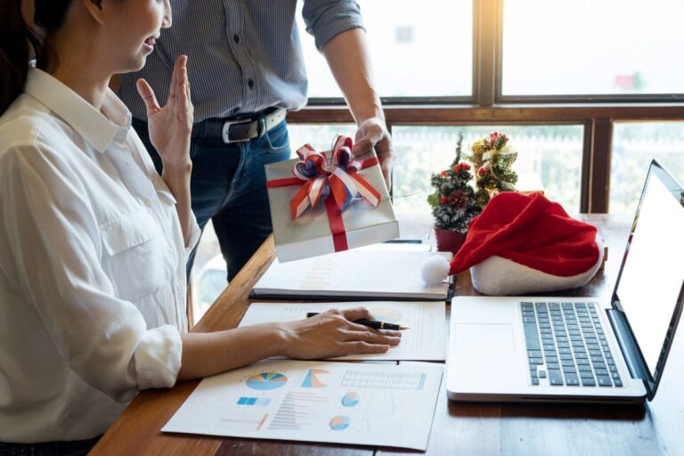 An office employee receiving christmas gift from her boss and feeling happy.