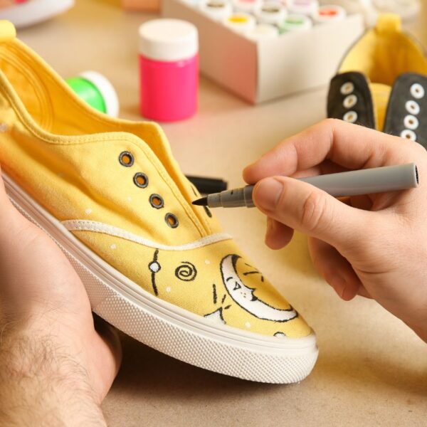 A person customizing his shoes by adding designs to it