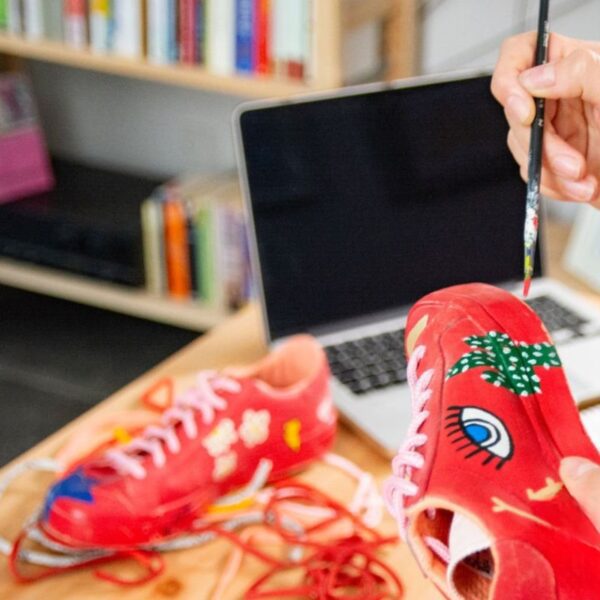 A person painting on shoes and selling them online