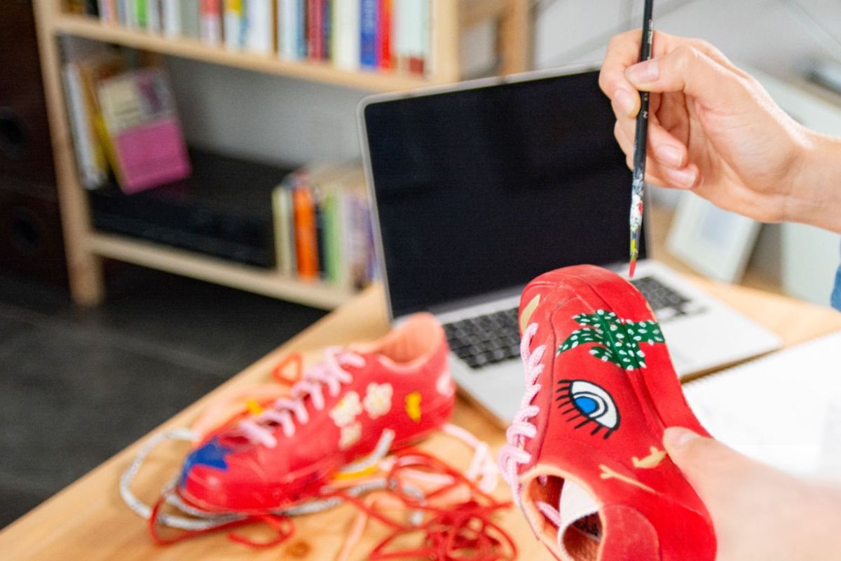 A person painting on shoes and selling them online