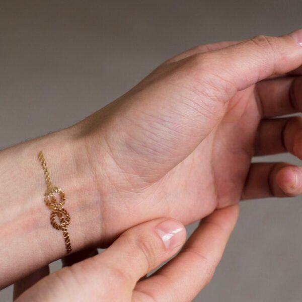 A women with a gold metallic custom tattoo on her hand made by swagify