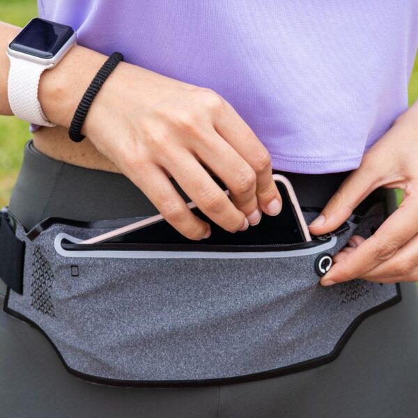 A lady is putting her phone in her custom fanny pack