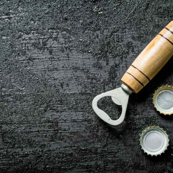 A wooden bottle opener kept with bottle caps