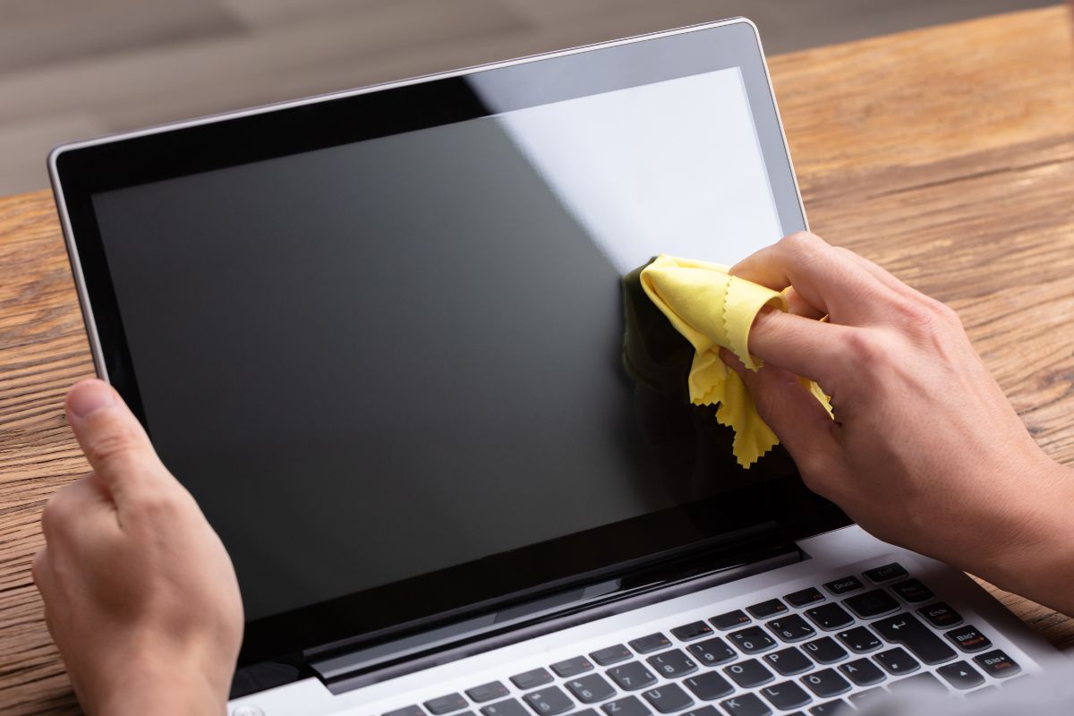 A person cleaning his laptop with the help of custom screen lens cleaners