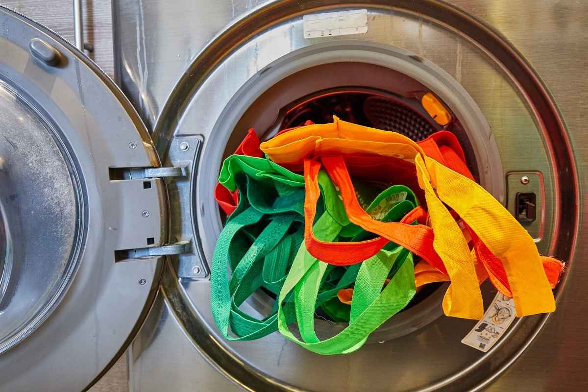 A collection of custom tote bags being washed in a washing machine