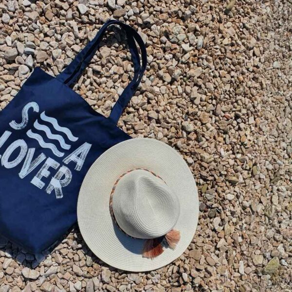 A custom beach tote bag resting near the shoreline