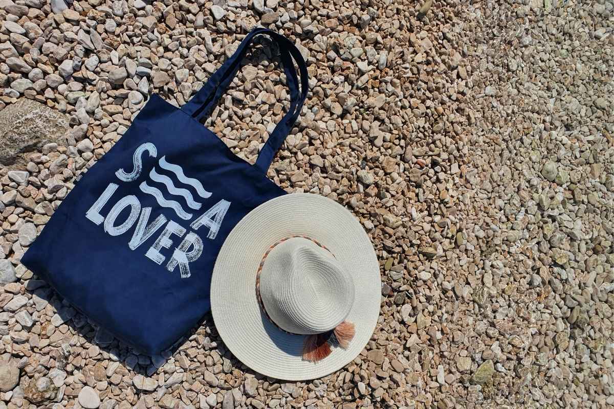 A custom beach tote bag resting near the shoreline