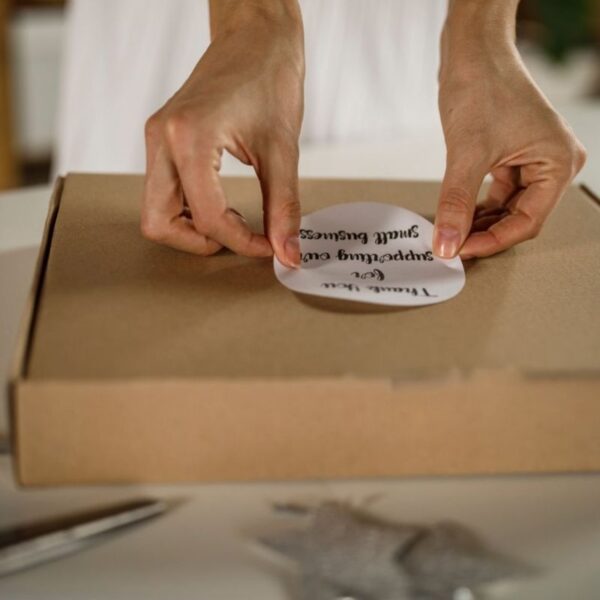 A lady pasting a custom sticker on her products to thank customers