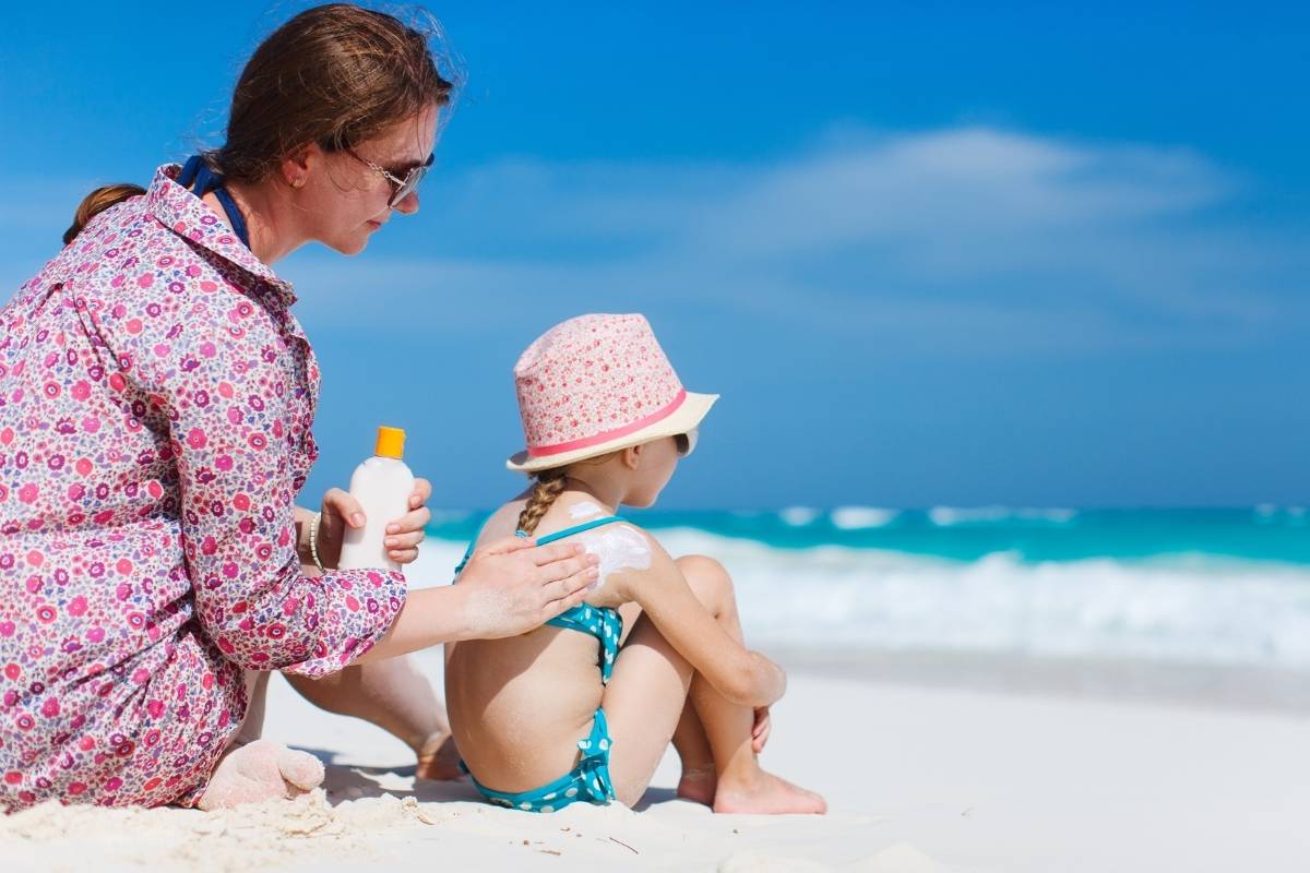 A mother applying sunscreen to her child to protect them from the sun