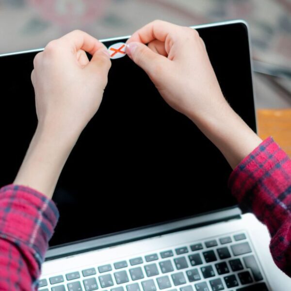 A person is using a homemade webcam cover on his laptop