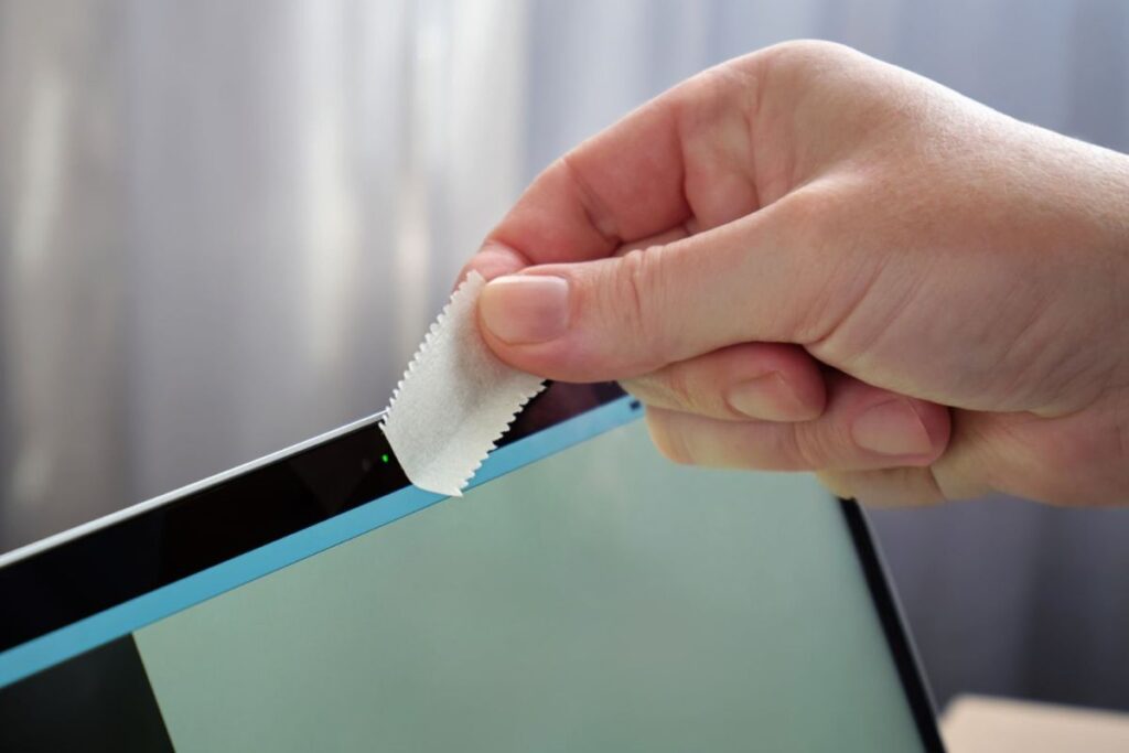 A person placing a sticker over the webcam to use it as a shield